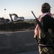 A Syrian Kurdish militia member of YPG patrols near a Turkish army tank as Turks work to build a new Ottoman tomb in the background in Esme village in Aleppo province, Syria, Sunday, Feb. 22, 2015. Turkey launched an overnight military operation into neighboring Syria to evacuate troops guarding an Ottoman tomb and to move the crypt to a new location, Turkish Prime Minister Ahmet Davutoglu said Sunday. Davutoglu said they plan to build a new Ottoman tomb in Esme village, close to Turkey-Syria border. (AP Photo/Mursel Coban, Depo Photos)